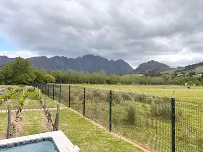 a fence in a field with mountains in the background at Cottage K'Gari in Franschhoek