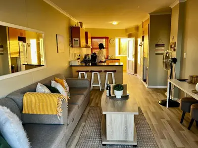a living room with a couch and a kitchen at Beachside Bliss Strand in Strand