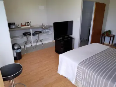 a bedroom with a bed and a flat screen tv at Fisherhaven Guest House in Hermanus