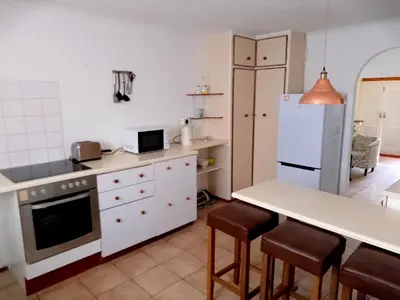a kitchen with a refrigerator and a table and chairs at Fisherhaven Guest House in Hermanus