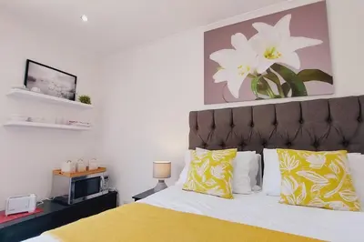 a bedroom with a bed with yellow and white pillows at Cosy Nest - Uncapped Wi-fi & Self Check-in in Cape Town