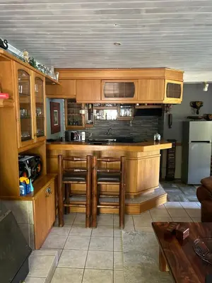 a kitchen with wooden cabinets and a bar with stools at Garden View Inn in Cape Town