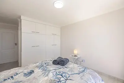 a bedroom with a bed with a blue and white blanket at Blouberg Pearl in Cape Town