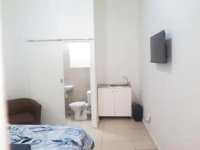 a bathroom with a bed and a toilet and a television at lodgeon91 in Cape Town