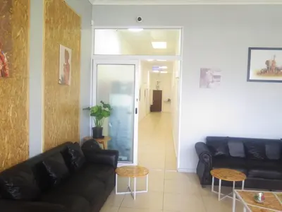 a living room with black leather couches and a hallway at lodgeon91 in Cape Town