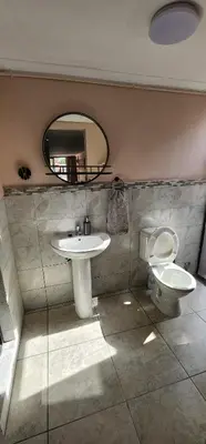 a bathroom with a sink and a toilet and a mirror at Cozy Batchelor Labiance in Cape Town