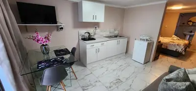 a kitchen with white cabinets and a glass table at Cozy Batchelor Labiance in Cape Town