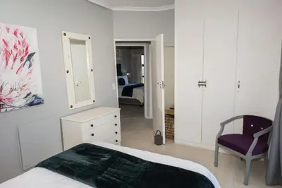 a bedroom with a bed and a chair and a mirror at Grandview Guesthouse in Cape Town