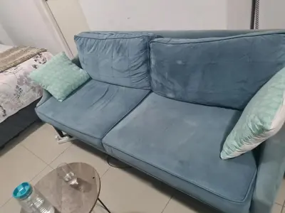 a blue couch in a living room with a table at Elikem Properties in Cape Town