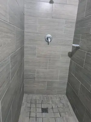 a bathroom with a shower with a tile floor at Elikem Properties in Cape Town