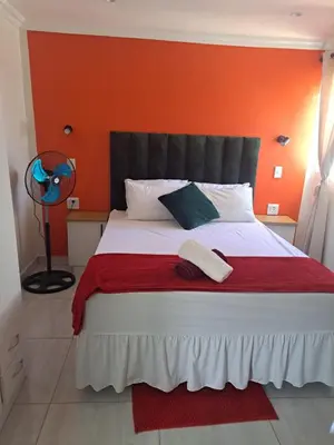 a bedroom with a bed with an orange wall at Olivia's guest house in Cape Town