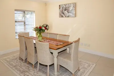 a dining room table with chairs and a vase of flowers at Lovely and Peaceful 3 bedroom house in Cape Town
