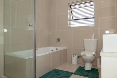 a bathroom with a tub and a toilet and a shower at Lovely and Peaceful 3 bedroom house in Cape Town