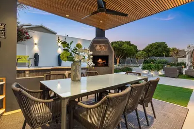 a patio with a table and chairs and a fireplace at Rancho Relaxo in Bloubergstrand
