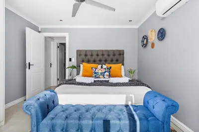 a bedroom with a large bed with a blue tufted couch at Rancho Relaxo in Bloubergstrand