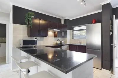 a kitchen with a black counter and a refrigerator at Waterstone East C103 by Host Agents in Cape Town