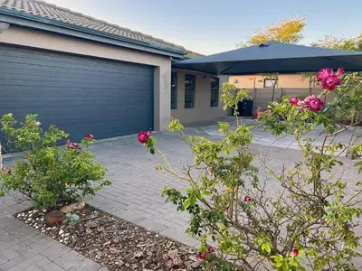 a house with a garage door and some flowers at 81 on Groenewoud in Cape Town