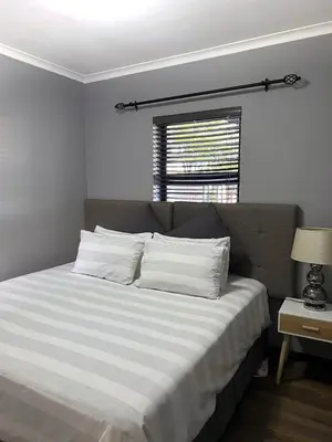 a bedroom with a bed with white sheets and a window at 81 on Groenewoud in Cape Town