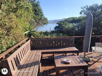 a wooden bench on a deck with a table and a surfboard at Milkwood Cabin Getaway in Lake Marina