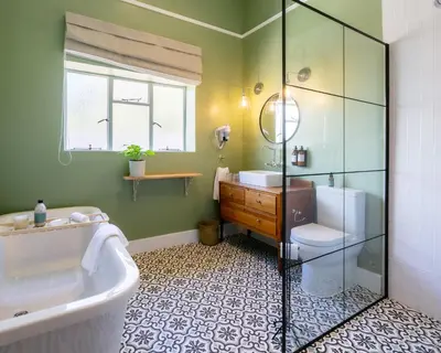 a bathroom with a tub and a sink and a toilet at The Belmont in Franschhoek