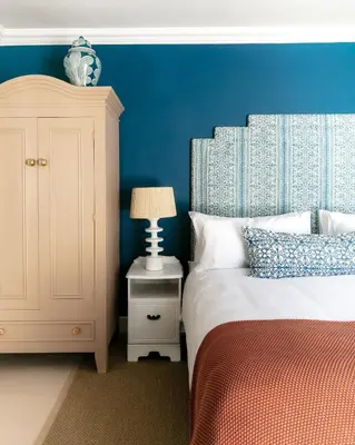 a bedroom with a bed and a blue wall at The Belmont in Franschhoek