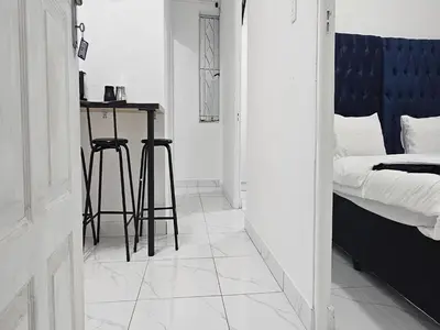 a bedroom with a bed and a table and stools at Goshen Lodge Fitzroy in Cape Town