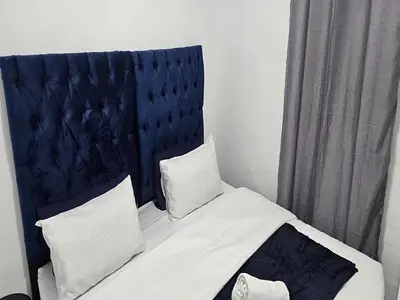 a bed with a blue headboard and two pillows at Goshen Lodge Fitzroy in Cape Town