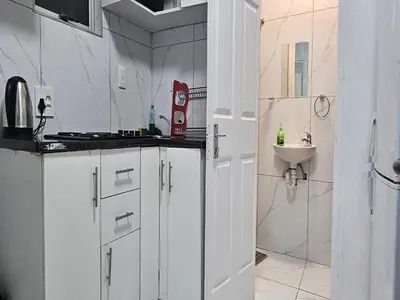 a white kitchen with a sink and a shower at Goshen Lodge Fitzroy in Cape Town