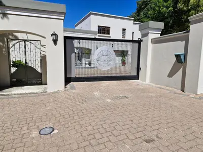 a white house with a gate and a driveway at The Botanical House in Somerset West