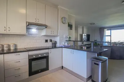 a kitchen with white cabinets and a stove top oven at 405 Portofino Eyrie Holiday Apartments in Cape Town