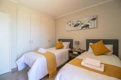two beds in a room with white and yellow at 405 Portofino Eyrie Holiday Apartments in Cape Town