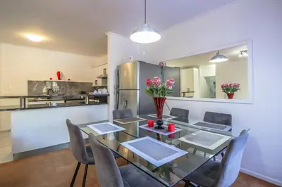 a dining room with a table and chairs and a kitchen at 102 Palma Eyrie Holiday Apartments in Cape Town