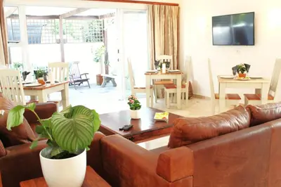 a living room with a leather couch and a table at 7th Wonder Beach Guest House in Cape Town