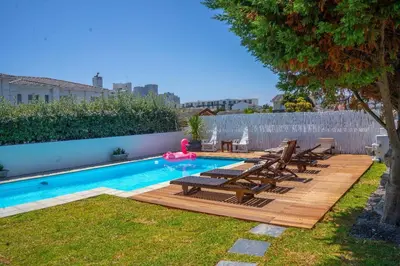 a backyard with a swimming pool and a wooden deck at 7th Wonder Beach Guest House in Cape Town