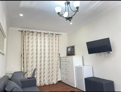 a living room with a couch and a flat screen tv at Tia Maria cottage in Cape Town