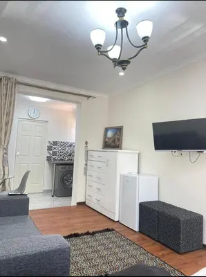 a living room with a couch and a flat screen tv at Tia Maria cottage in Cape Town