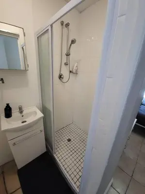 a shower with a glass door next to a sink and a toilet at Fynbosrus on Grotto in Hermanus