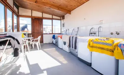 a laundry room with washing machines and a table at Strand Apartment only 30 meters from beach in Cape Town