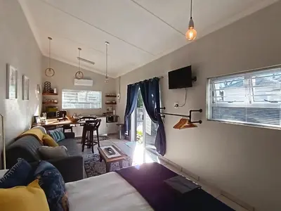 a living room with a bed and a dining room at Dalau on Main in Paarl