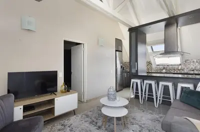 a living room with a couch and a tv and a table at Dolphin Beach H301 by Host Agents in Bloubergstrand