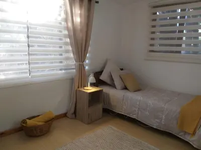a bedroom with a bed and a window at Santika Getaway Cottage Stellenbosch in Stellenbosch