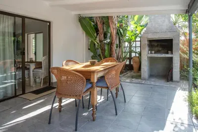 a wooden table and chairs on a patio with a fireplace at Santika Getaway Cottage Stellenbosch in Stellenbosch
