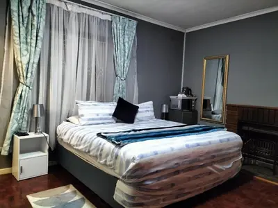 a bedroom with a large bed with a mirror at Step-by-Step Self-Catering and B&B in Bellville