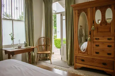 a bedroom with a dresser and a mirror and a chair at Kolonie's Tuin in Stellenbosch