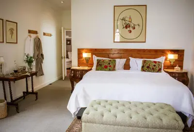 a bedroom with a large white bed and a bench at Kolonie's Tuin in Stellenbosch