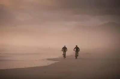 two people riding bikes on the beach in the sand at Tuis en Tevrede - 1 Bedroom Flat in Hermanus