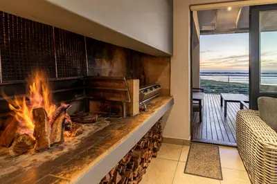 a fireplace in a living room with a view of the ocean at Hermanus Beach House at CShine in Hermanus