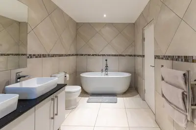 a bathroom with a tub and a sink and a toilet at Hermanus Beach House at CShine in Hermanus