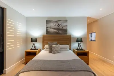 a bedroom with a large bed and two lamps at Hermanus Beach House at CShine in Hermanus