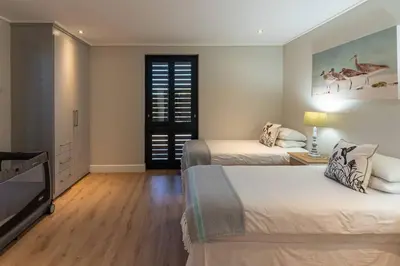 a bedroom with two beds and a flat screen tv at Hermanus Beach House at CShine in Hermanus